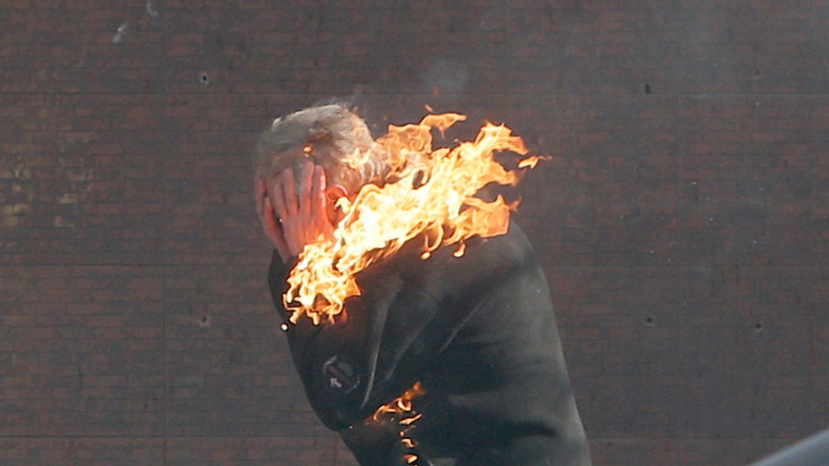 En demonstrant försöker springa undan och släcka sina brinnande kläder.